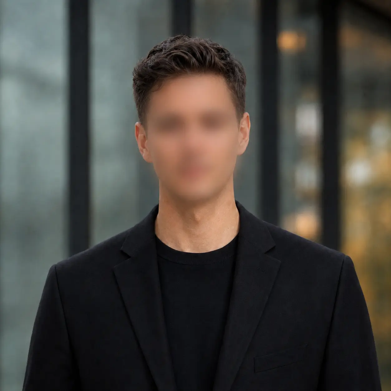 An anonymous prospective founder in a dark blazer, photographed against a modern architectural background with their face intentionally blurred.