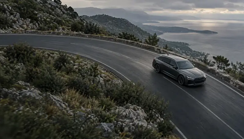 A dark car on a winding coastal road